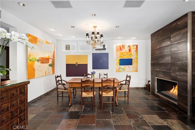 dining room featuring a fireplace, stone tile floors, recessed lighting, a chandelier, and baseboards