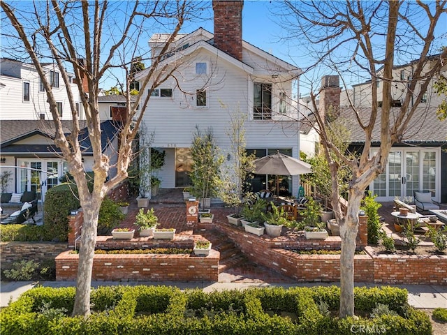 view of front of house with french doors, a chimney, and a patio area