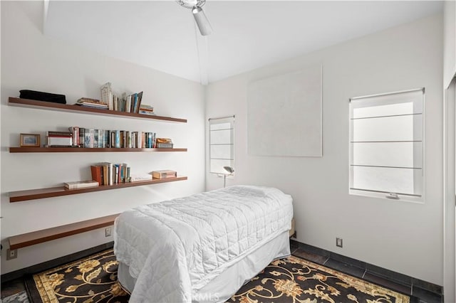 bedroom featuring lofted ceiling, dark tile patterned floors, baseboards, and a ceiling fan