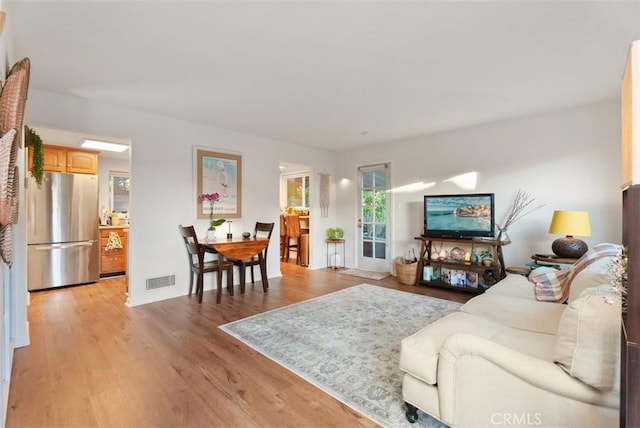 living area featuring light wood-style floors and visible vents