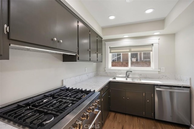 kitchen featuring recessed lighting, under cabinet range hood, dark wood-type flooring, a sink, and appliances with stainless steel finishes