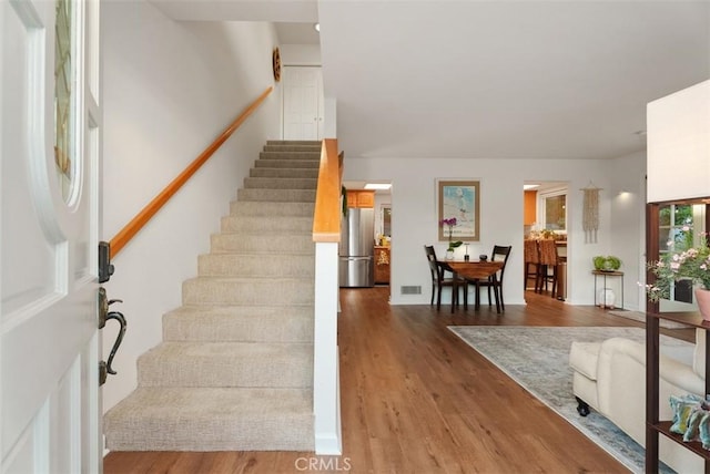 staircase featuring wood finished floors and visible vents