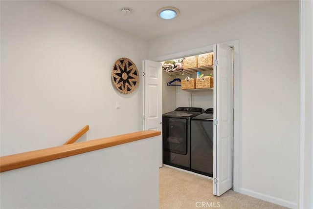 clothes washing area with laundry area, light carpet, baseboards, and washing machine and clothes dryer