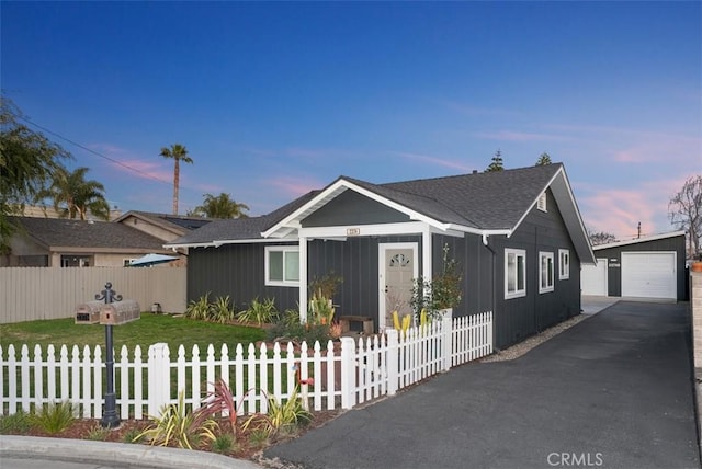 view of front of home with a fenced front yard, an outbuilding, and a garage