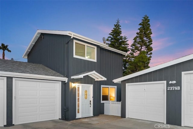 view of front of house featuring a garage, concrete driveway, and roof with shingles