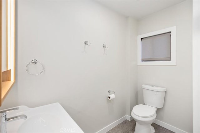 bathroom with toilet and baseboards