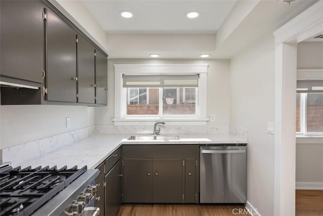 kitchen with a healthy amount of sunlight, dishwasher, a sink, and wood finished floors