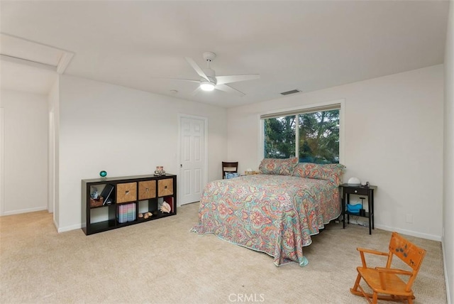 carpeted bedroom with ceiling fan, attic access, visible vents, and baseboards