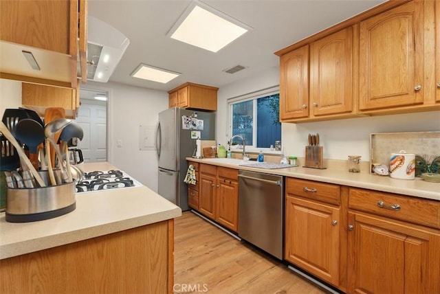 kitchen featuring stainless steel appliances, brown cabinetry, and light countertops