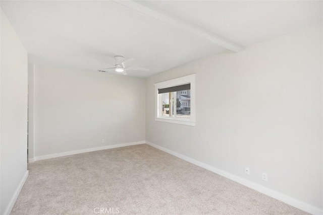 empty room featuring carpet, baseboards, a ceiling fan, and beamed ceiling