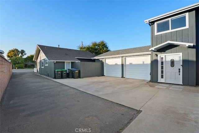 view of front of house featuring board and batten siding, concrete driveway, fence, and a garage