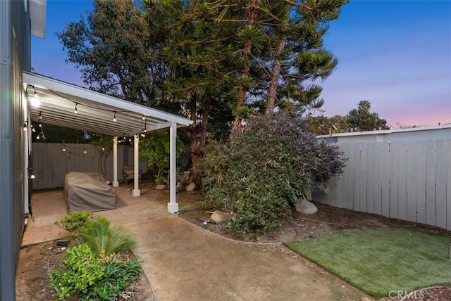 yard at dusk with a patio and a fenced backyard