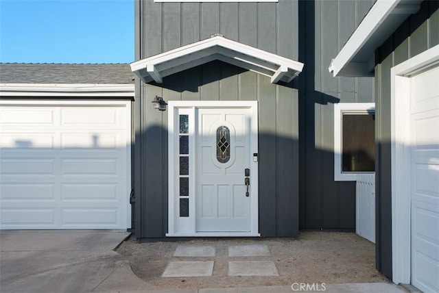 property entrance with a garage, board and batten siding, and roof with shingles