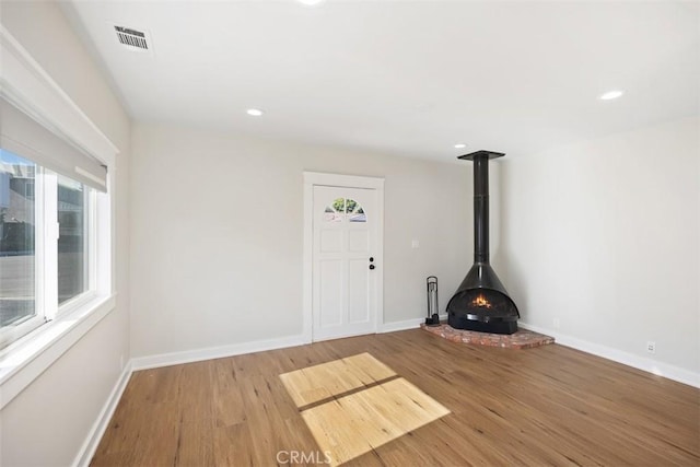 entrance foyer featuring wood finished floors, a wood stove, and baseboards