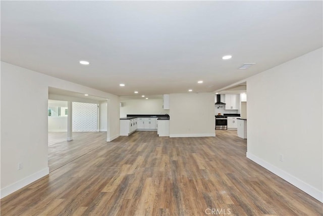 unfurnished living room featuring baseboards, wood finished floors, and recessed lighting