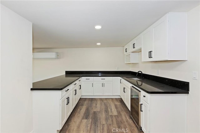 kitchen featuring wine cooler, wood finished floors, a sink, a wall mounted AC, and dark countertops