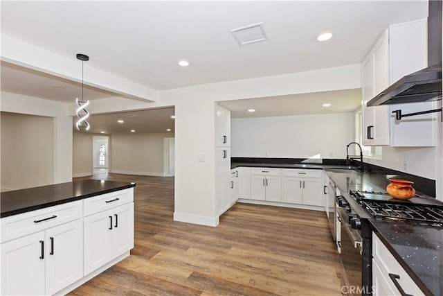 kitchen featuring a sink, visible vents, black gas stove, light wood-type flooring, and wall chimney exhaust hood