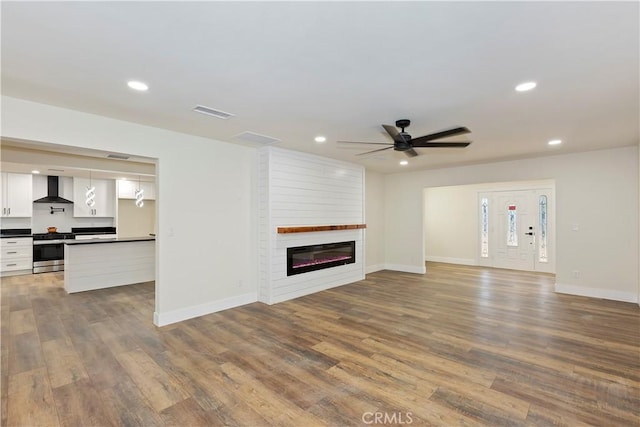 unfurnished living room with dark wood-type flooring, a fireplace, visible vents, and recessed lighting