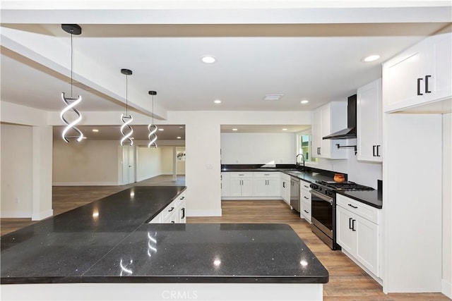 kitchen with white cabinets, light wood-style flooring, appliances with stainless steel finishes, wall chimney range hood, and a sink