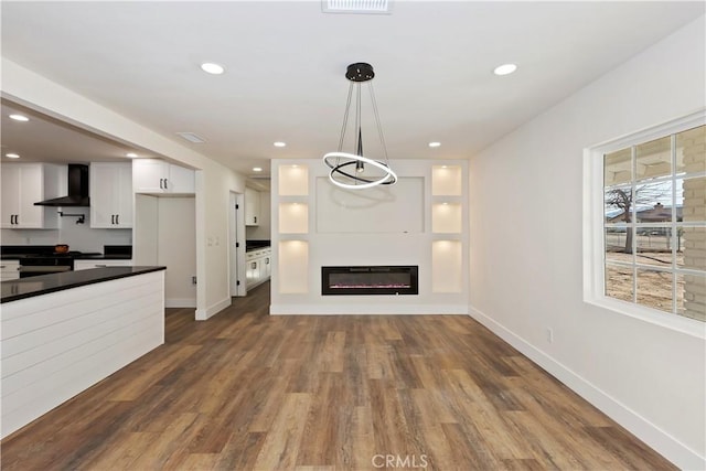 unfurnished living room featuring recessed lighting, baseboards, dark wood-style flooring, and a glass covered fireplace