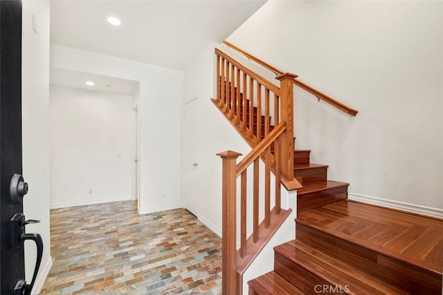 stairway with brick floor, recessed lighting, and baseboards