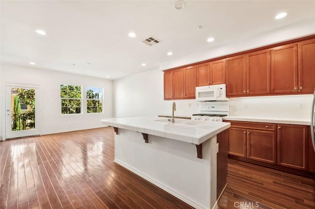 kitchen with visible vents, white appliances, a sink, and tile counters