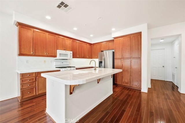 kitchen featuring brown cabinetry, white appliances, visible vents, and tile countertops