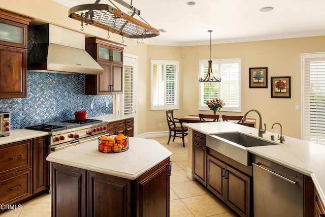 kitchen featuring wall chimney exhaust hood, ornamental molding, a sink, stainless steel appliances, and backsplash