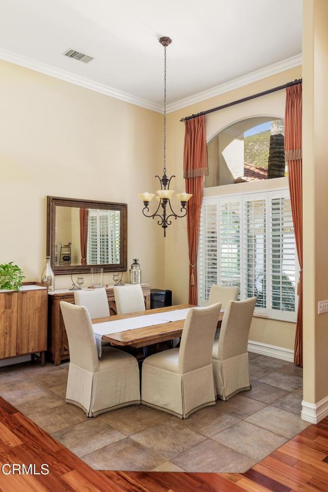 dining area with visible vents, an inviting chandelier, light wood-style floors, ornamental molding, and baseboards