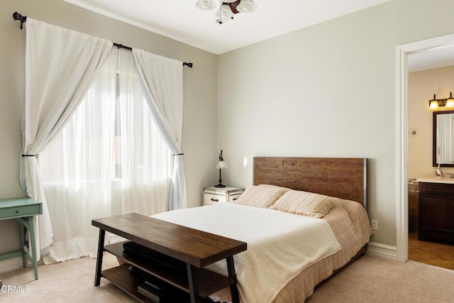 bedroom featuring light colored carpet, ensuite bath, and baseboards