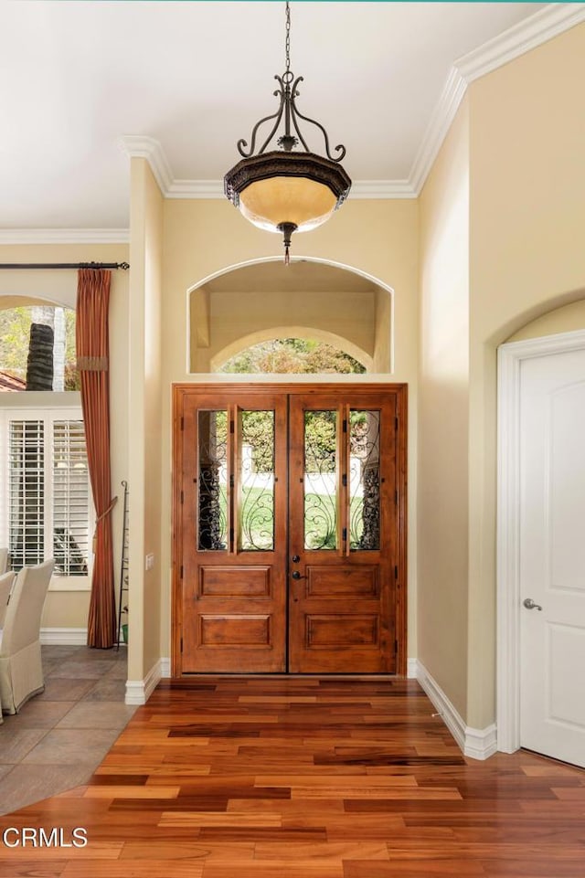 foyer featuring baseboards, ornamental molding, and wood finished floors