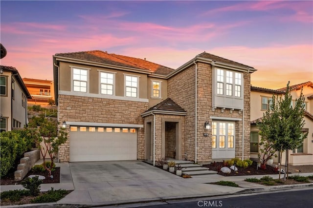 view of front of house featuring driveway, stone siding, an attached garage, and stucco siding