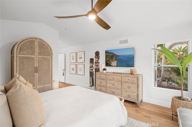 bedroom featuring lofted ceiling, visible vents, baseboards, a ceiling fan, and light wood finished floors