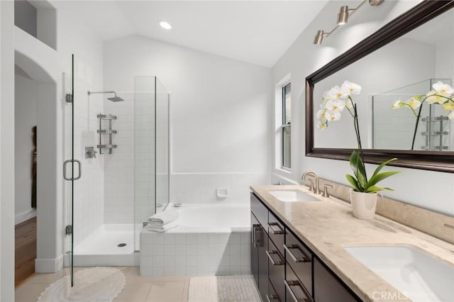 bathroom featuring lofted ceiling, tile patterned floors, a garden tub, a shower stall, and a sink