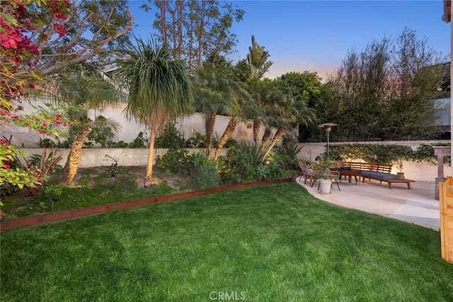 yard at dusk featuring a patio area and fence