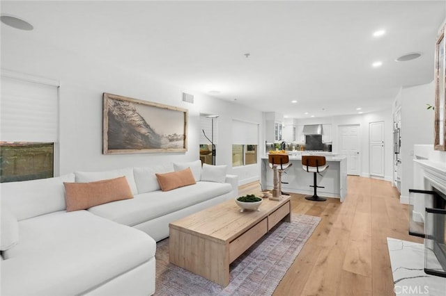 living room with baseboards, light wood finished floors, visible vents, and recessed lighting