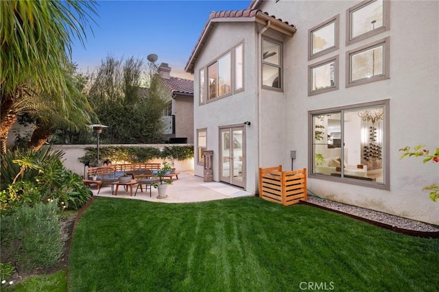 back of house with a tile roof, a yard, stucco siding, outdoor lounge area, and a patio area