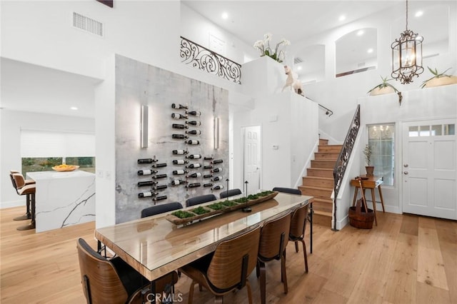 dining room with a towering ceiling, light wood-style floors, and stairs