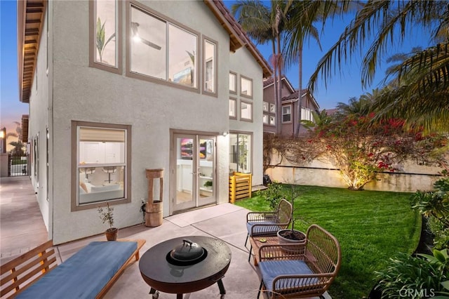 rear view of house with a yard, french doors, a patio, and stucco siding