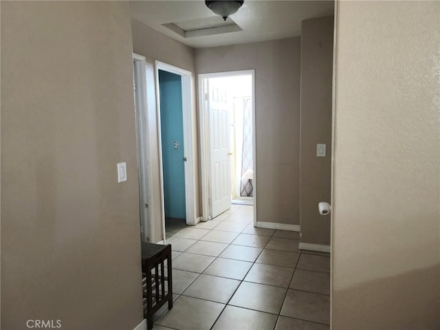 hall with baseboards and light tile patterned floors