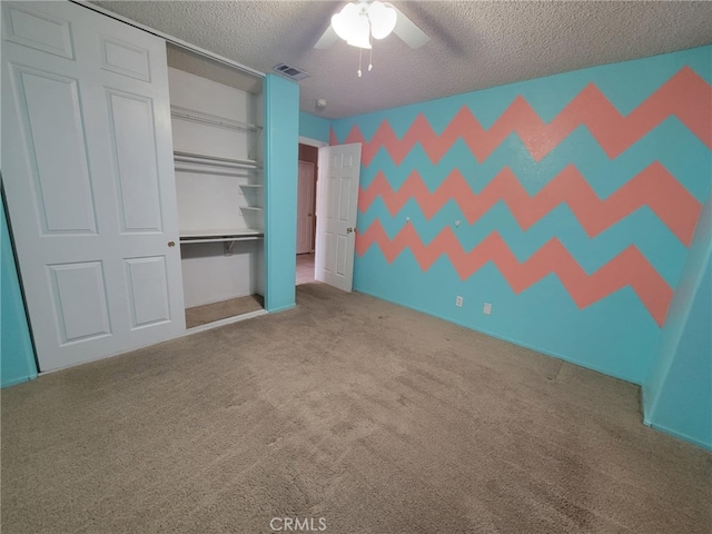 unfurnished bedroom featuring a textured ceiling, visible vents, carpet, a ceiling fan, and a closet