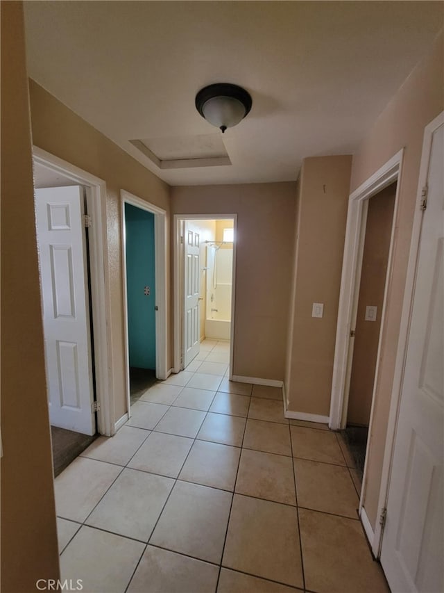 hall featuring baseboards and light tile patterned floors