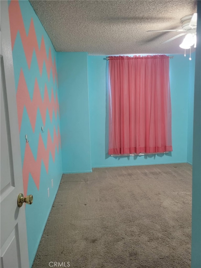 carpeted spare room with a textured ceiling and ceiling fan