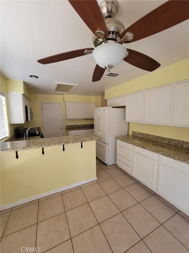 kitchen with ceiling fan, visible vents, stainless steel microwave, freestanding refrigerator, and white cabinetry