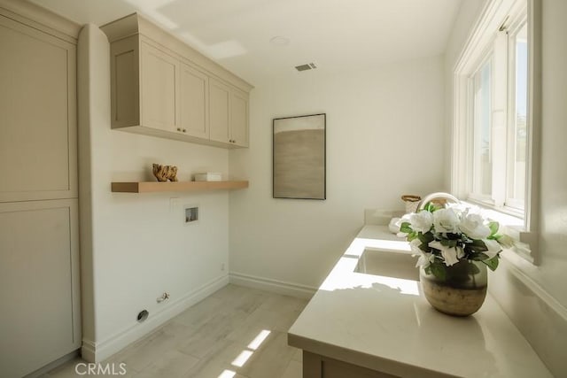 washroom featuring hookup for a washing machine, visible vents, baseboards, cabinet space, and light wood-style floors