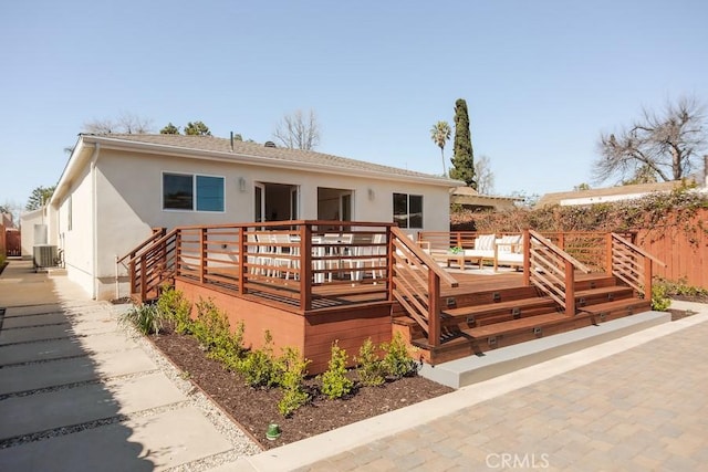 view of front of house with stucco siding, a wooden deck, and central AC