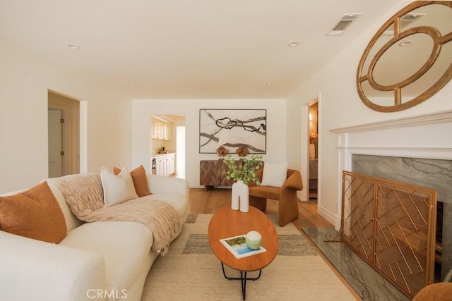 living area with visible vents, wood finished floors, and a high end fireplace