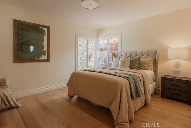 bedroom with light wood-type flooring and baseboards