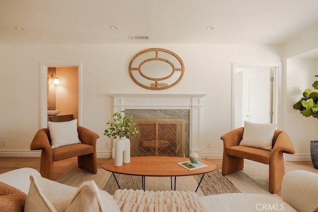 living area with light wood-type flooring, recessed lighting, visible vents, and a premium fireplace