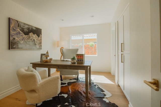 office space with light wood-type flooring and baseboards